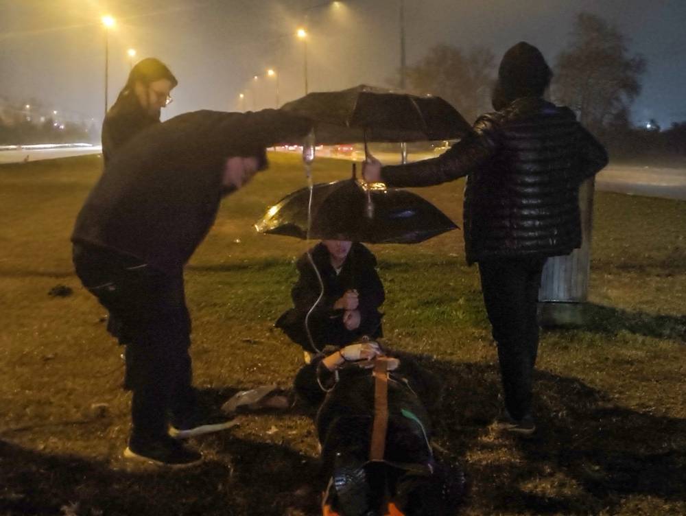 Kazada yaralanan kadın ıslanmasın diye şemsiye ile başında beklediler